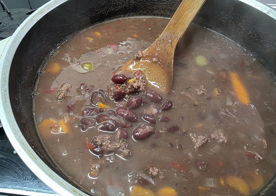 Olla con frijol, zanahoria y cuchara de madera